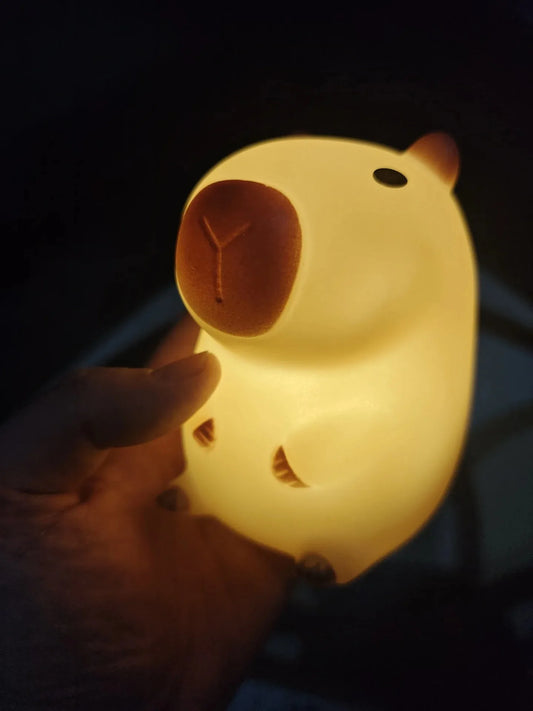 Hand holding a glowing cat-shaped night light against a dark background