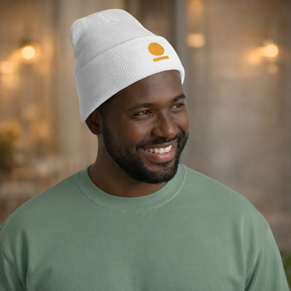 Man wearing a white puffer jacket and STOIC beanie with embroidered logo on a city street.