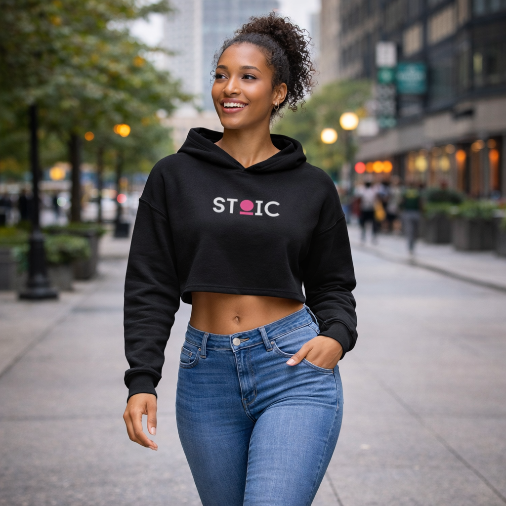 Woman wearing a black STOIC hoodie with embroidered logo on a city street