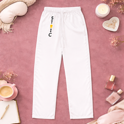 White sweatpants with vertical 'STOIC' logo on a pink surface with decorative items.