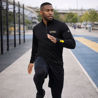Man wearing a black embroidered STOIC Quarter-Zip pullover with logo on his left chest and left wrist in running in a city street..