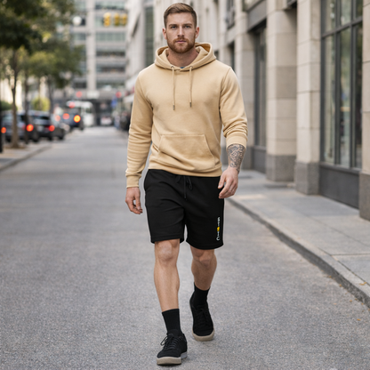 Man walking on a city street wearing a beige hoodie and black shorts with embroidered STOIC brand logo vertical, and black sneakers.