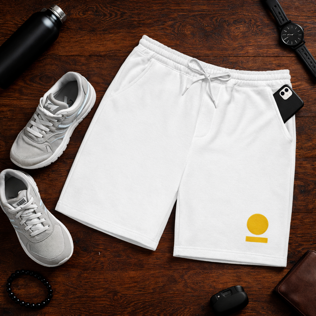 White STOIC shorts with embroidered brand logo on let thigh to the side, on a wooden surface, surrounded by white sneakers and other items.
