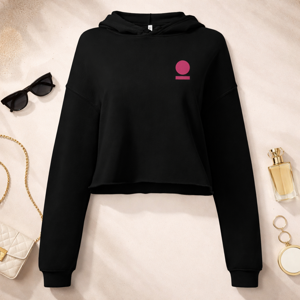 Black STOIC crop hoodie with a pink logo on a light beige surface with accessories around