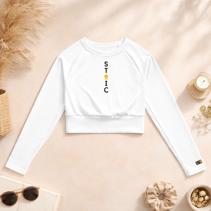 White long-sleeve crop top with 'STOIC' branding on a beige surface with decorative items.