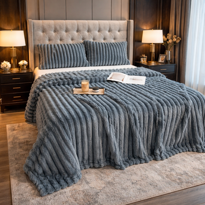 Dark gray grounding throw on a bed in a bedroom setting with lamps and decor.