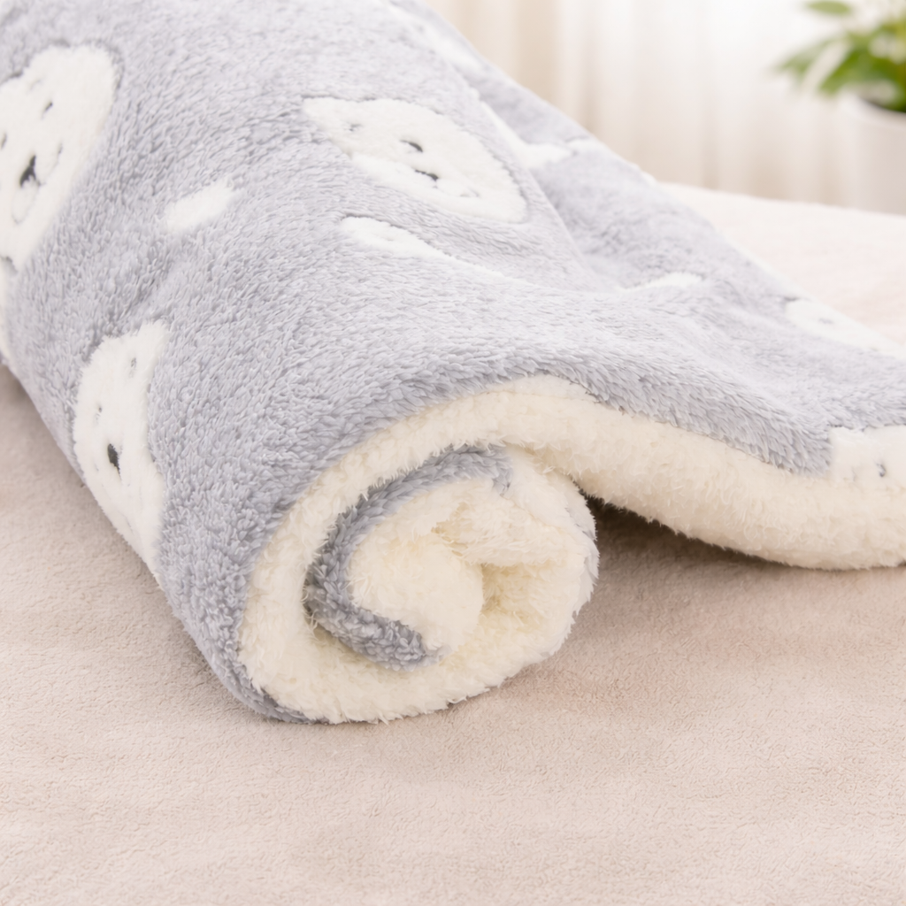 Rolled-up gray and white fleece Flannel Pet Sleeping Mat on a light surface