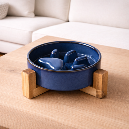 Blue ceramic slow-feed bowl with wooden stand on a wooden table