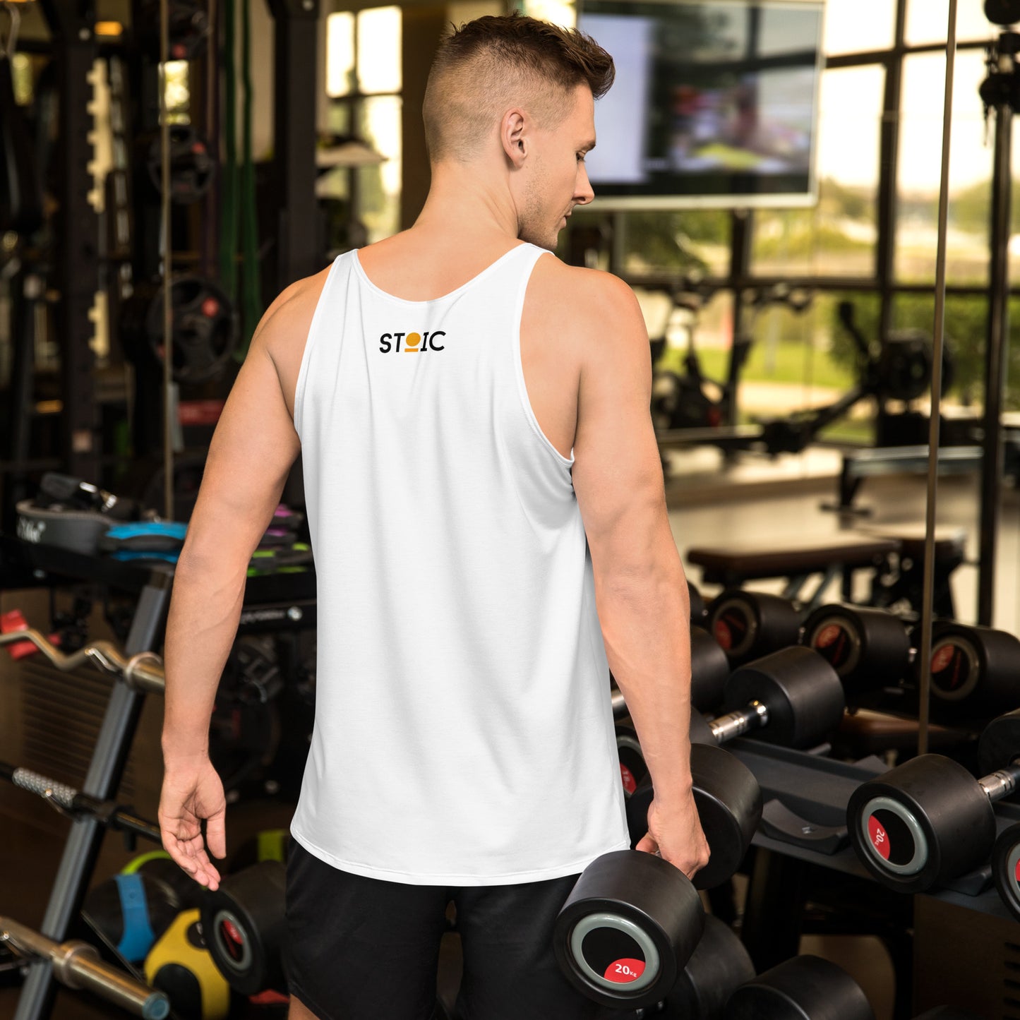 Man in a gym wearing a white tank top with 'STOIC' branding on his back.