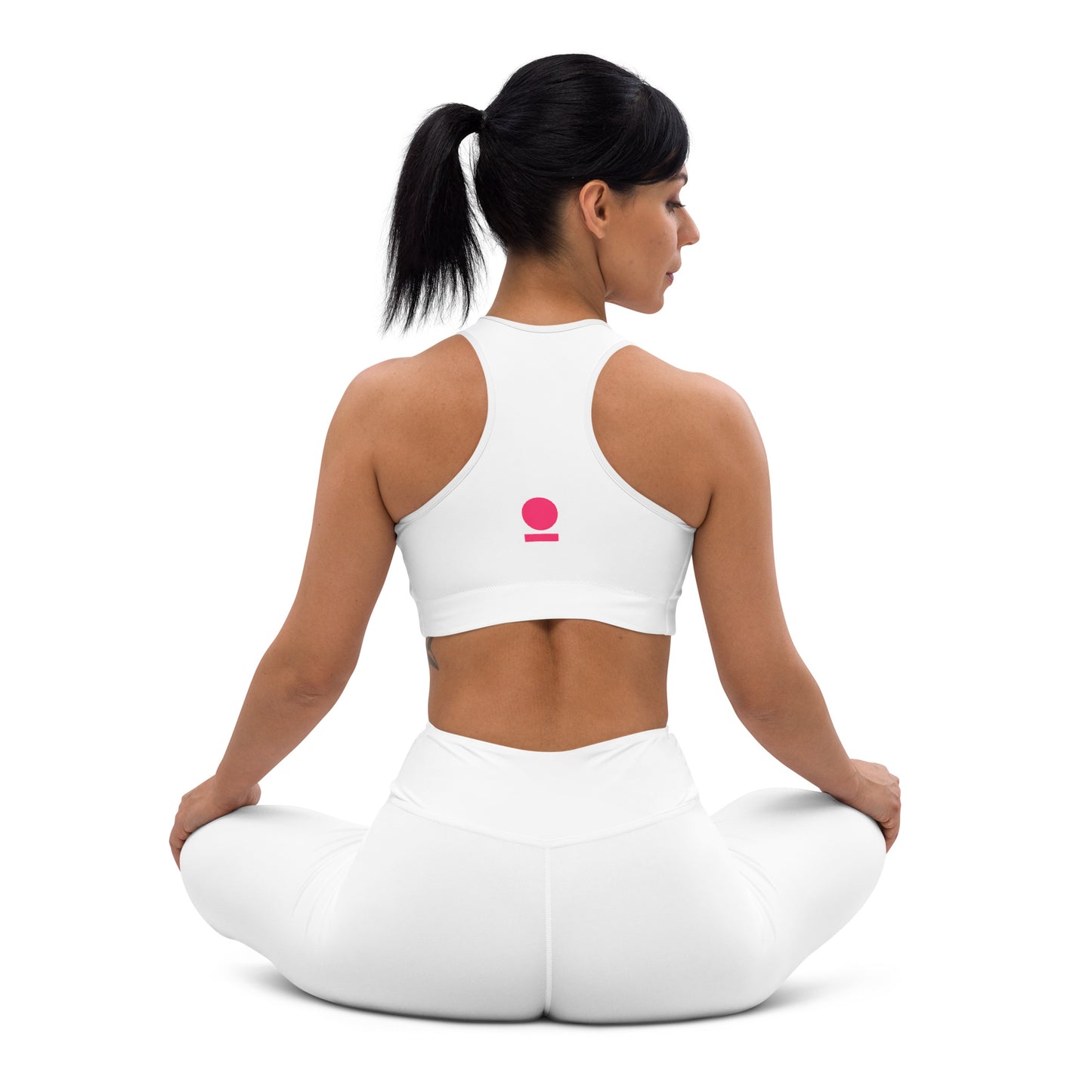 Woman sitting on a white yoga mat with a white STOIC sports bra featuring a pink logo.