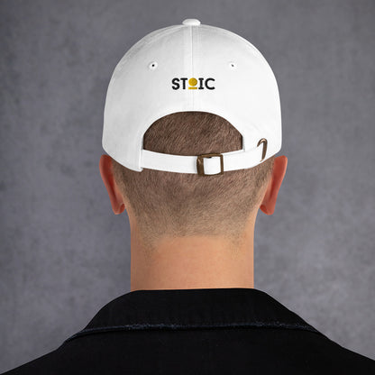 Person wearing a white STOIC cap with embroidered logo on a gray background