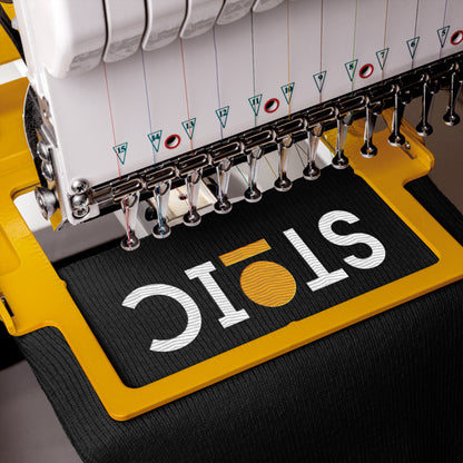 Embroidery machine with a partially completed logo on a black fabric